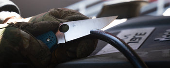 A mechanic using a knife to slice a line.