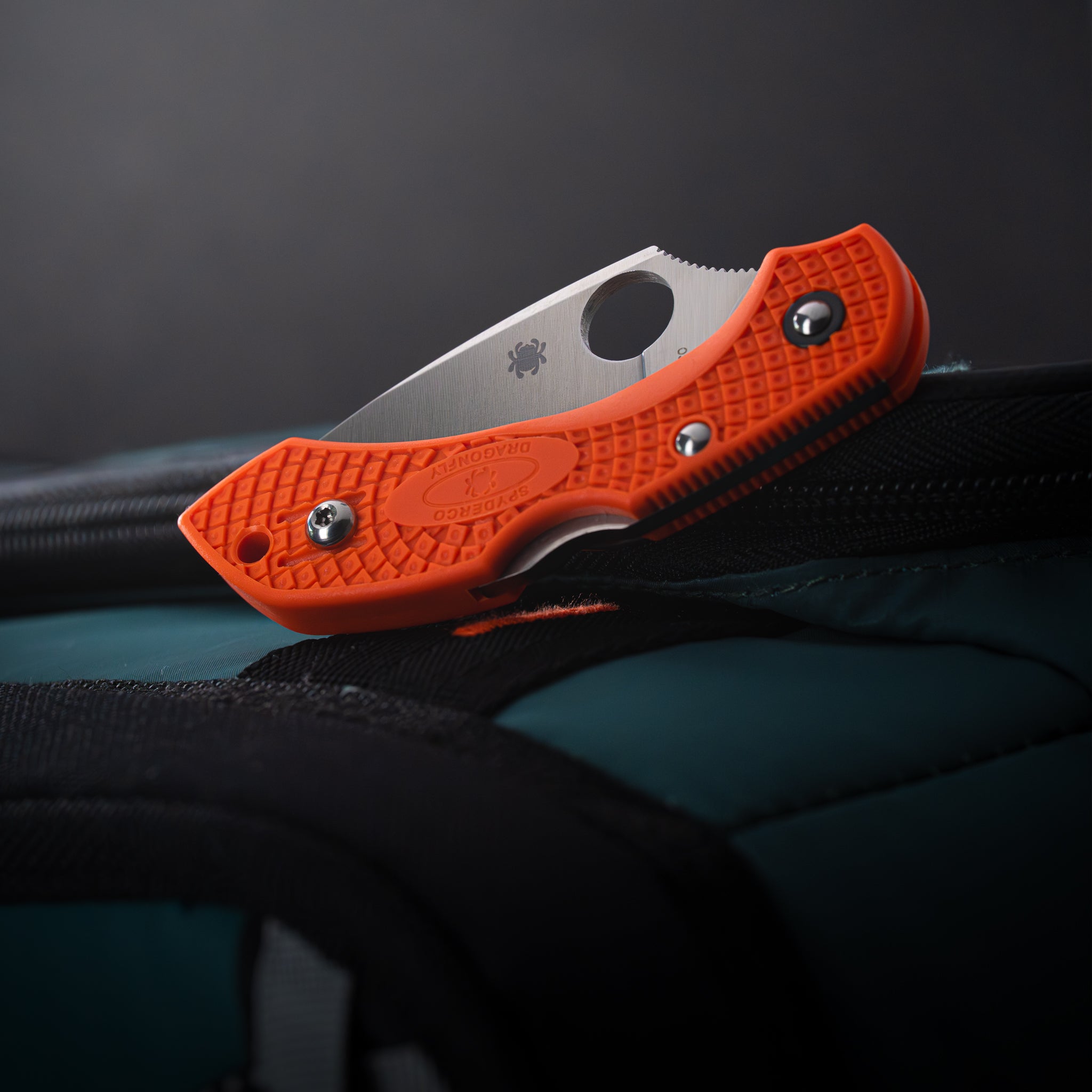 A close up of a closed folding knife on a soft cooler.